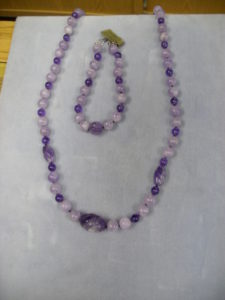 1254-	Multi color Amethysts round bead necklace with a large carved oval dark Amethysts center and two medium sized dark carved ovals.  It has matching bracelet.  Gorgeous colors.