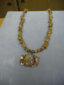 1243- This is a Picture of Jasper round and chip bead necklace with a large oval Picture Jasper set in a fancy gold filled frame. Wonderful with any shade of browns, oranges, or beige. People will ask, “What are those beads”.